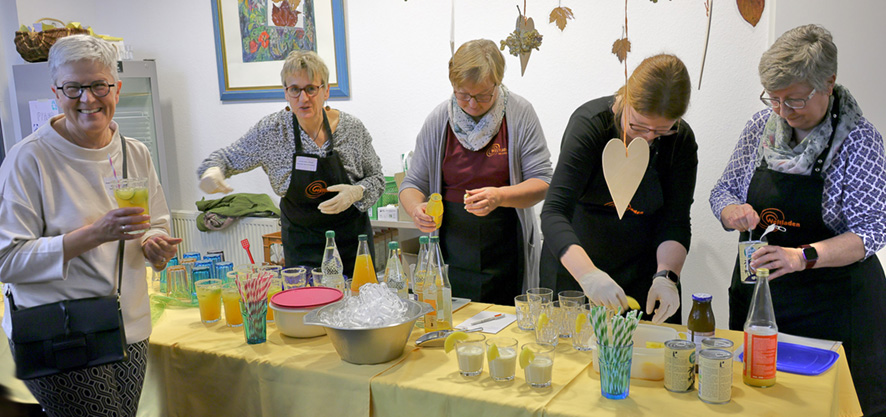 2024_10_Faire Cocktails zum Jubiläum Ehrenamtliche beim Zubereiten von bunten Cocktails