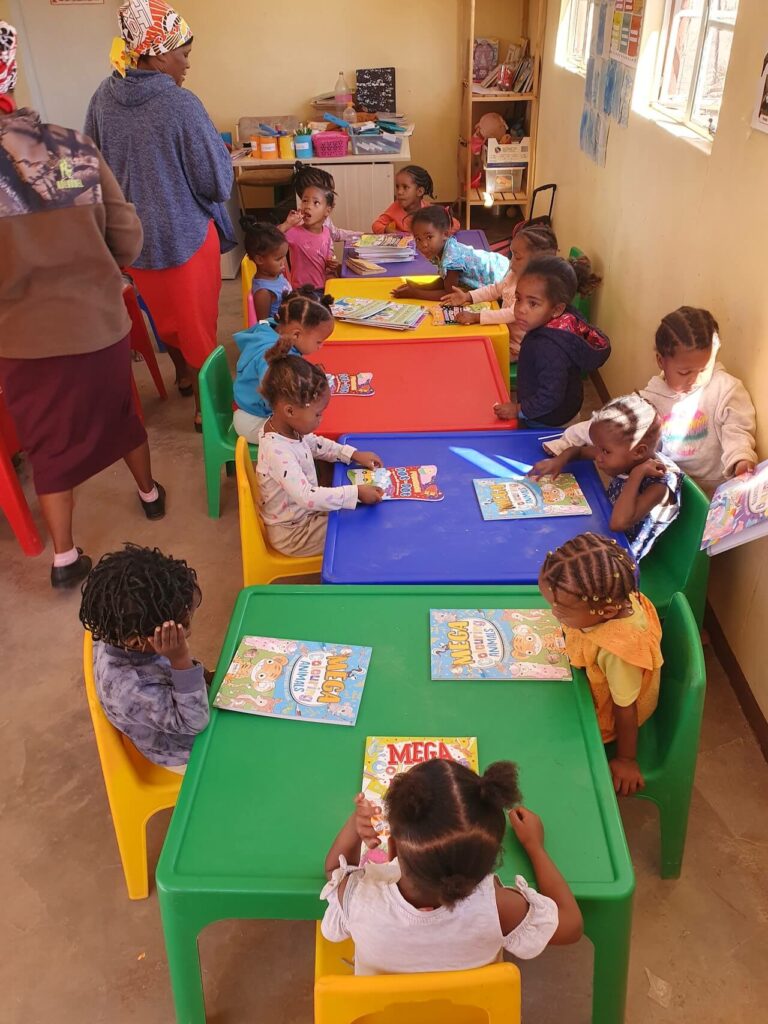Kinder und Lehrer mit Malheften im Kinderheim Maltahöhe in Namibia.
